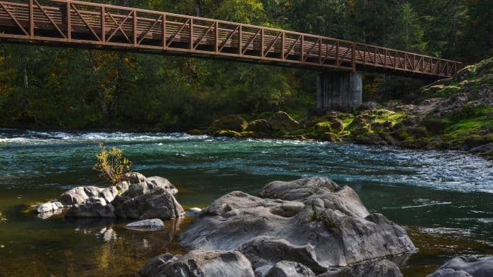 Greenwaters Park pedestrian bridge crossing clear blue-green Willamette River water near Oakridge Oregon