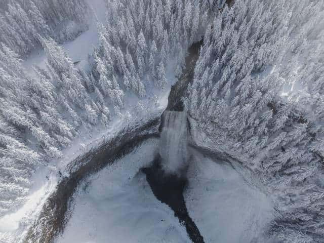Aerial view of Salt Creek Falls cascading through a snowy evergreen forest near Oakridge Oregon